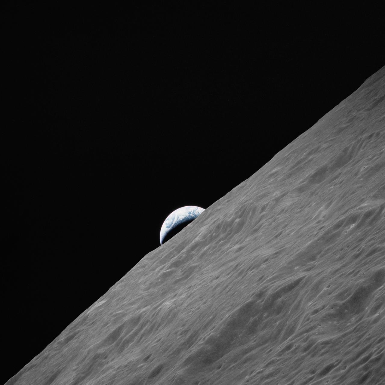A crescent Earth rising over the grey, cratered horizon of the Moon, seen from Apollo 17 in lunar orbit.